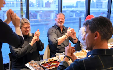 Friends learning sushi making in Asakusa, Tokyo, with cityscape view.