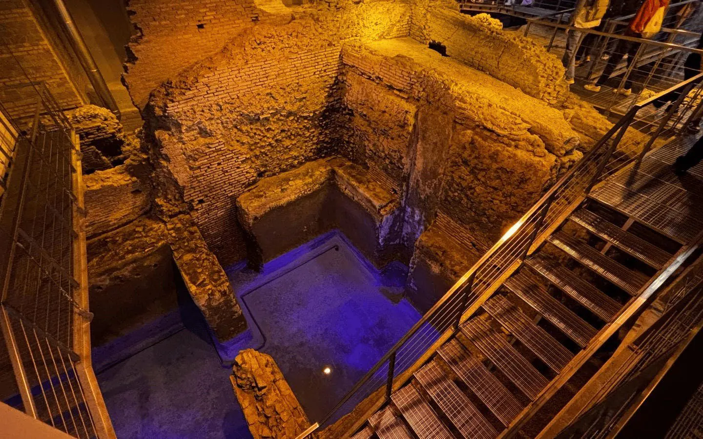 Subterranean aqueduct ruins beneath Piazza Navona, Rome, with ancient brick walls and metal walkways.