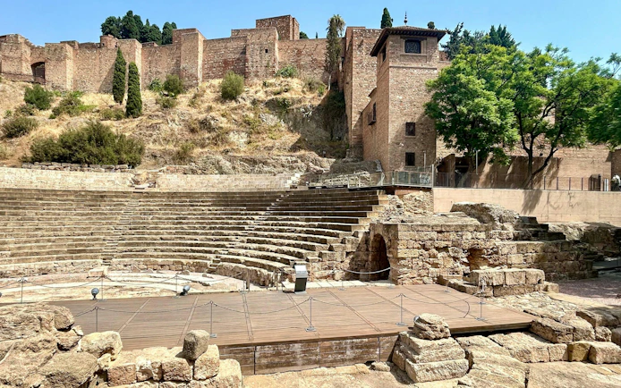 Roman Theatre ruins in Málaga with Alcazaba fortress in the background.