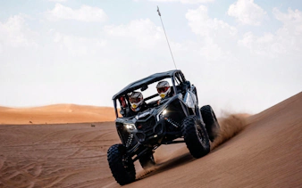 4-seater desert buggy driving on sand dunes during safari adventure.