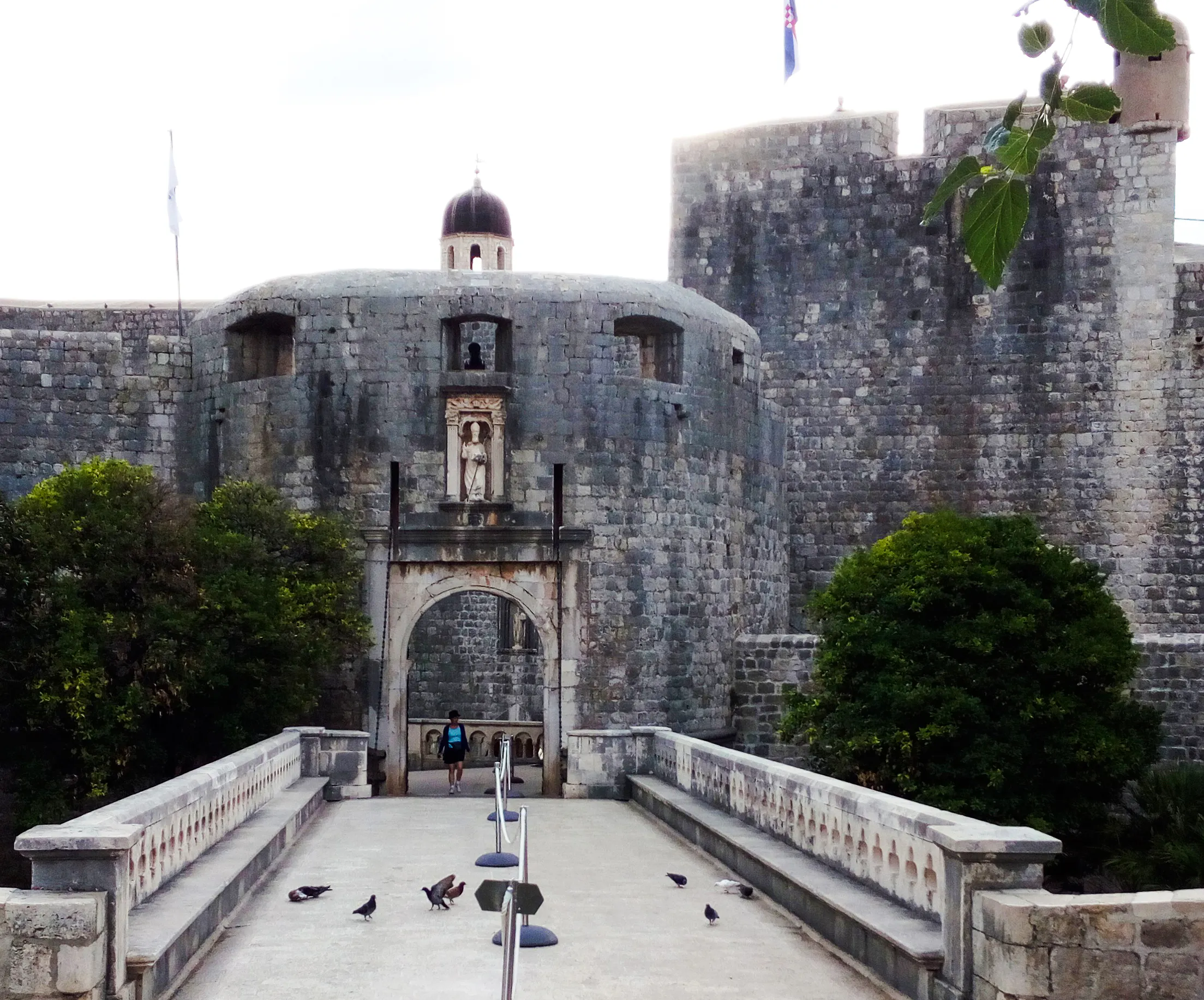 Entrance to Dubrovnik's historic city walls with stone archway and walkway.