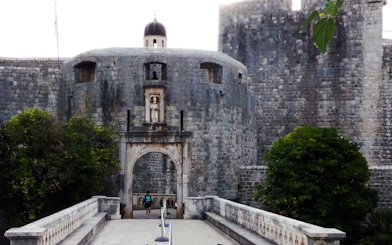 Entrance to Dubrovnik's historic city walls with stone archway and walkway.
