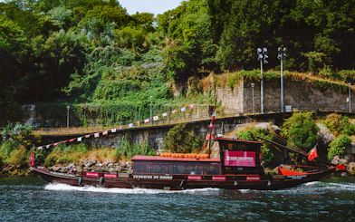 Tourist enjoying a boat ride on the Douro River in Porto, Portugal, with lush greenery in the background.
