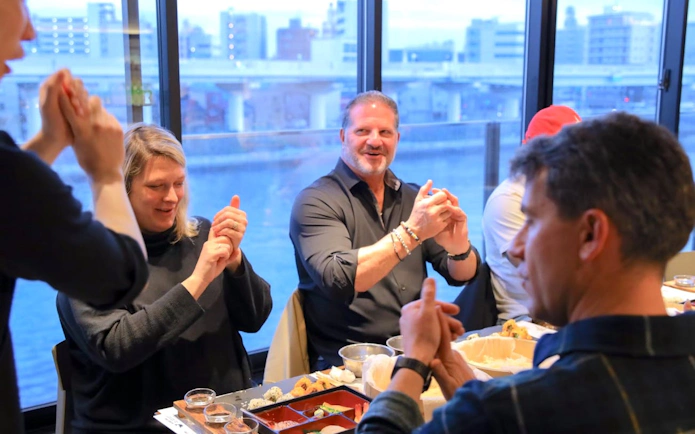 Participants learning sushi-making in Osaka cooking class with city view.