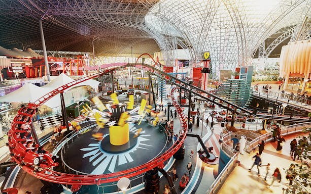 Ferrari World Abu Dhabi indoor roller coaster with visitors exploring attractions.