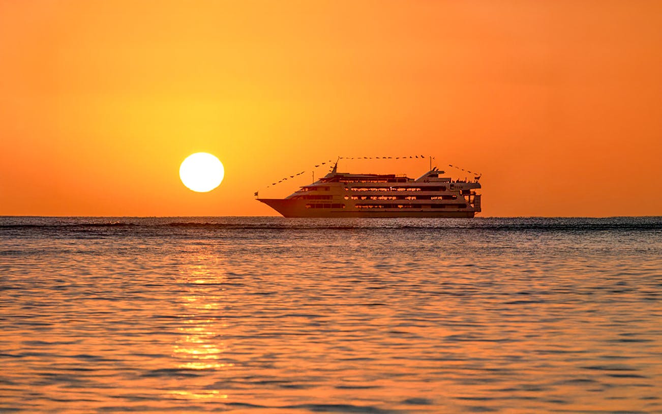 Star of Honolulu cruise ship at sunset with amber sky and ocean.