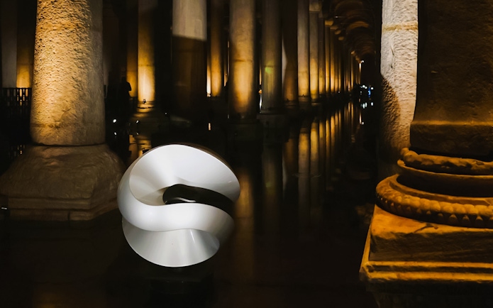 Basilica Cistern interior with illuminated columns and modern sculpture.