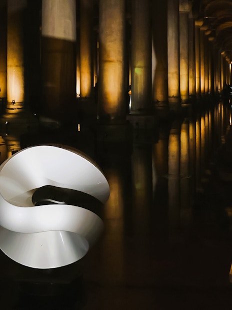 Basilica Cistern interior with illuminated columns and modern sculpture.