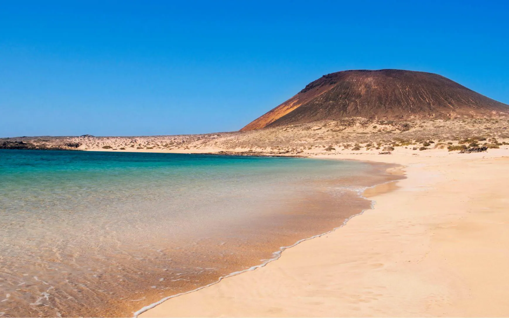 Playa de La Francesa beach with clear water and volcanic landscape, Lanzarote.