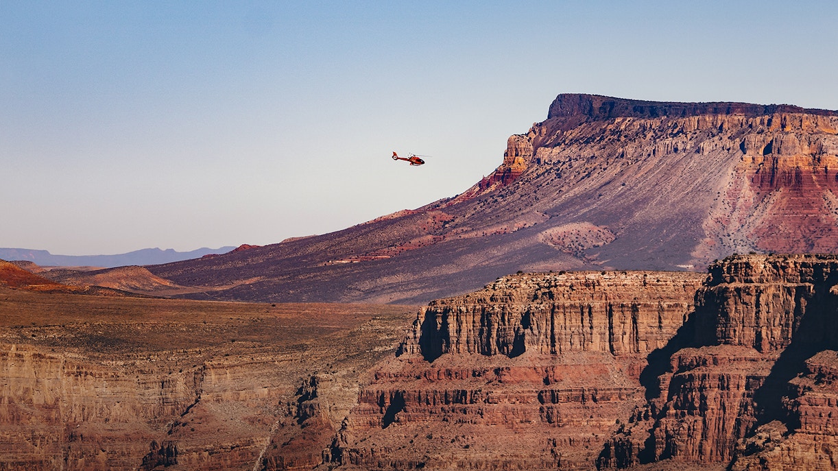 Helicopter flying over Grand Canyon West Rim, showcasing Arizona's vast landscape.