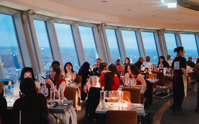 People dining at the Berlin TV Tower restaurant with city views.
