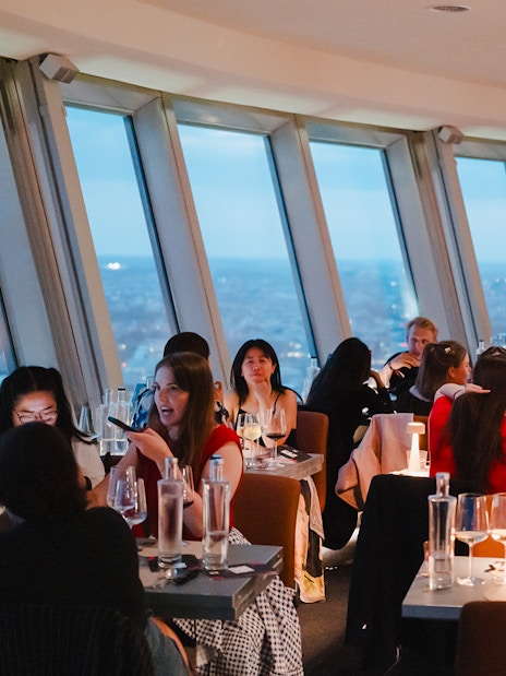 People dining at the Berlin TV Tower restaurant with city views.