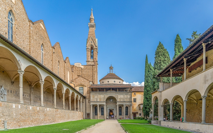Santa Croce courtyard in Florence with bell tower and arches.