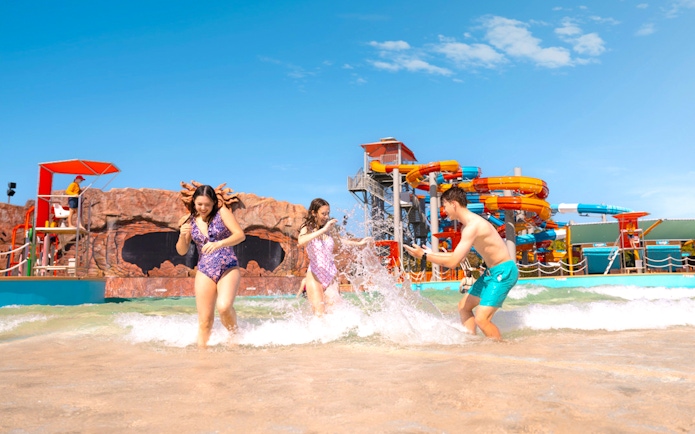 People enjoying the wave pool at Whitewater World with colorful slides in the background.