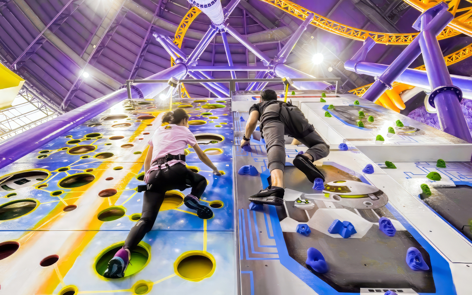 People climbing a colorful indoor rock wall at Berjaya Times Square Theme Park.