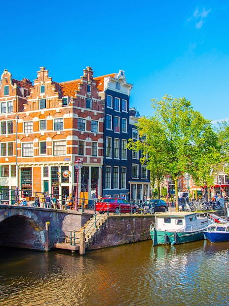 Amsterdam canal with historic buildings and boats, part of a self-guided walking tour.