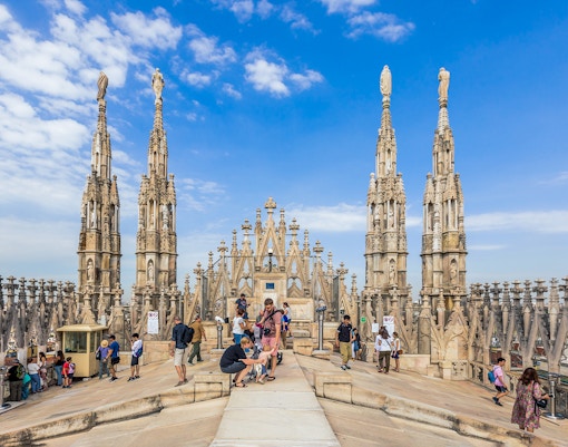 Small group with guide on Duomo of Milan rooftop, surrounded by spires.