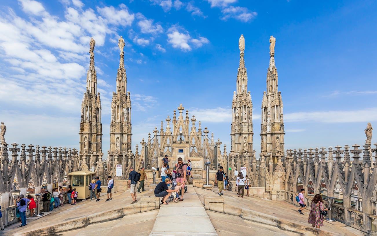 Small group with guide on Duomo of Milan rooftop, surrounded by spires.