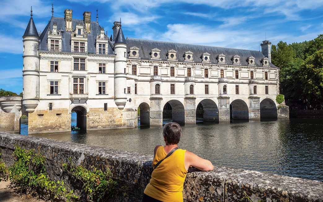 Person admiring Château de Chenonceau over the Cher River, Loire Valley.