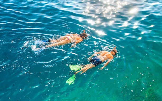 Two people snorkeling in clear blue water.