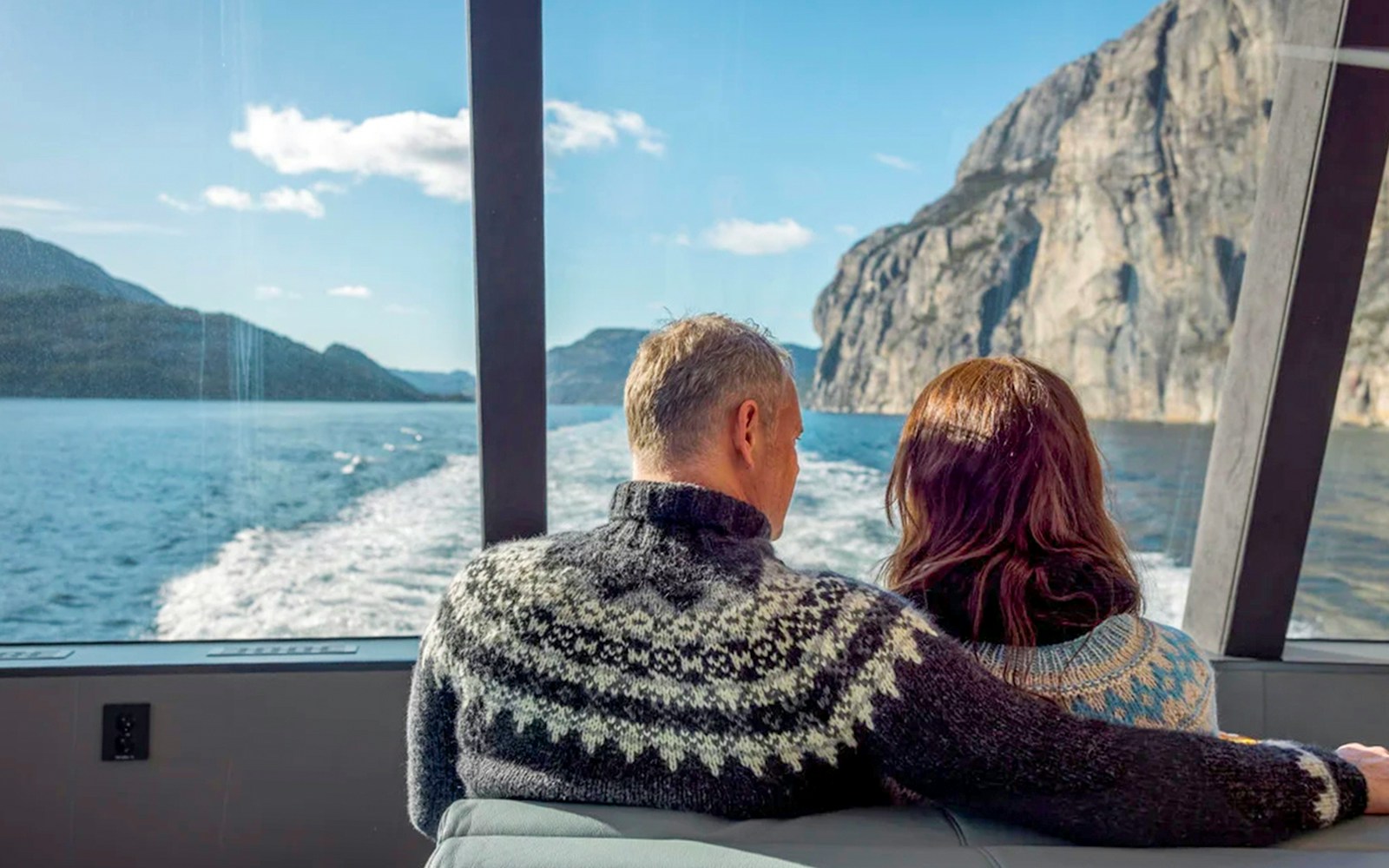 Guests on Lysefjord cruise from Stavanger, viewing cliffs and water through boat window.