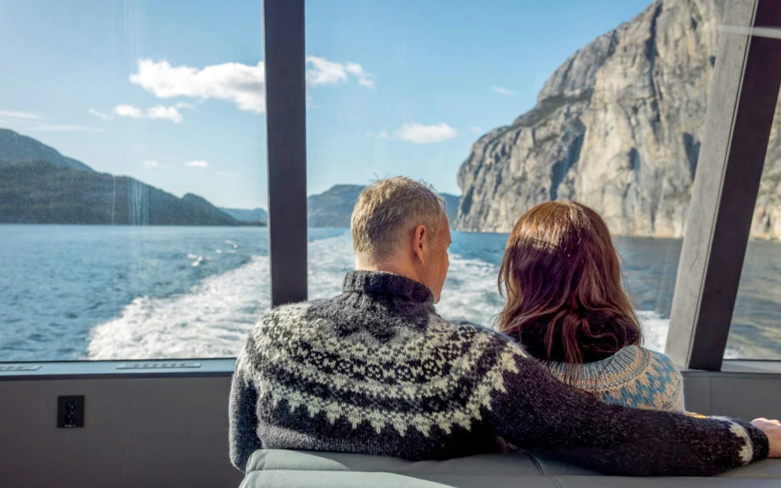 Guests on Lysefjord cruise from Stavanger, viewing cliffs and water through boat window.