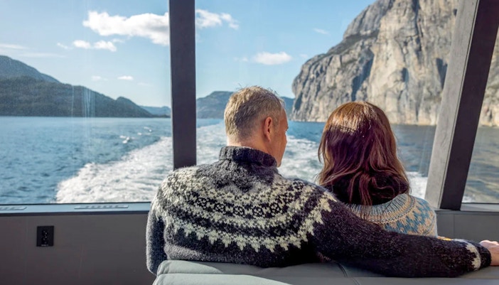 Guests on a boat cruise through Lysefjord, Norway, with scenic views of cliffs and waterfalls.