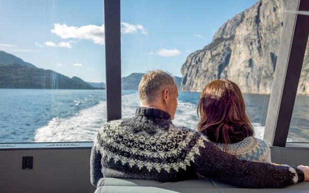Guests on Lysefjord cruise from Stavanger, viewing cliffs and water through boat window.