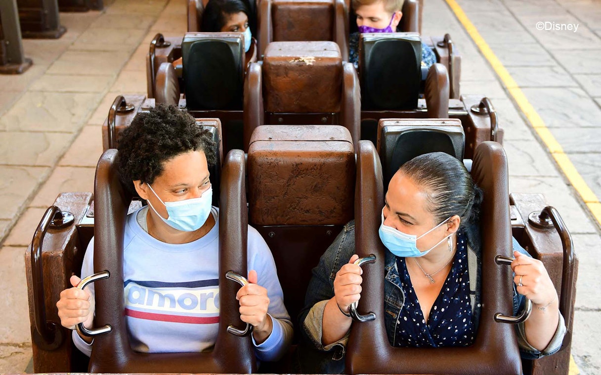 Guests on a roller coaster at Disneyland Paris wearing masks.