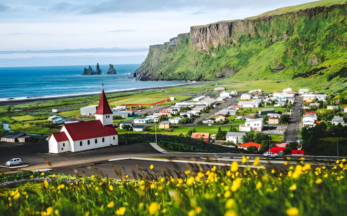 Coastal village of Vík í Mýrdal with church and cliffs on Iceland's south coast.