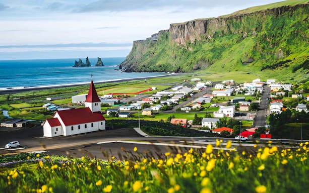 Coastal village of Vík í Mýrdal with church and cliffs on Iceland's south coast.