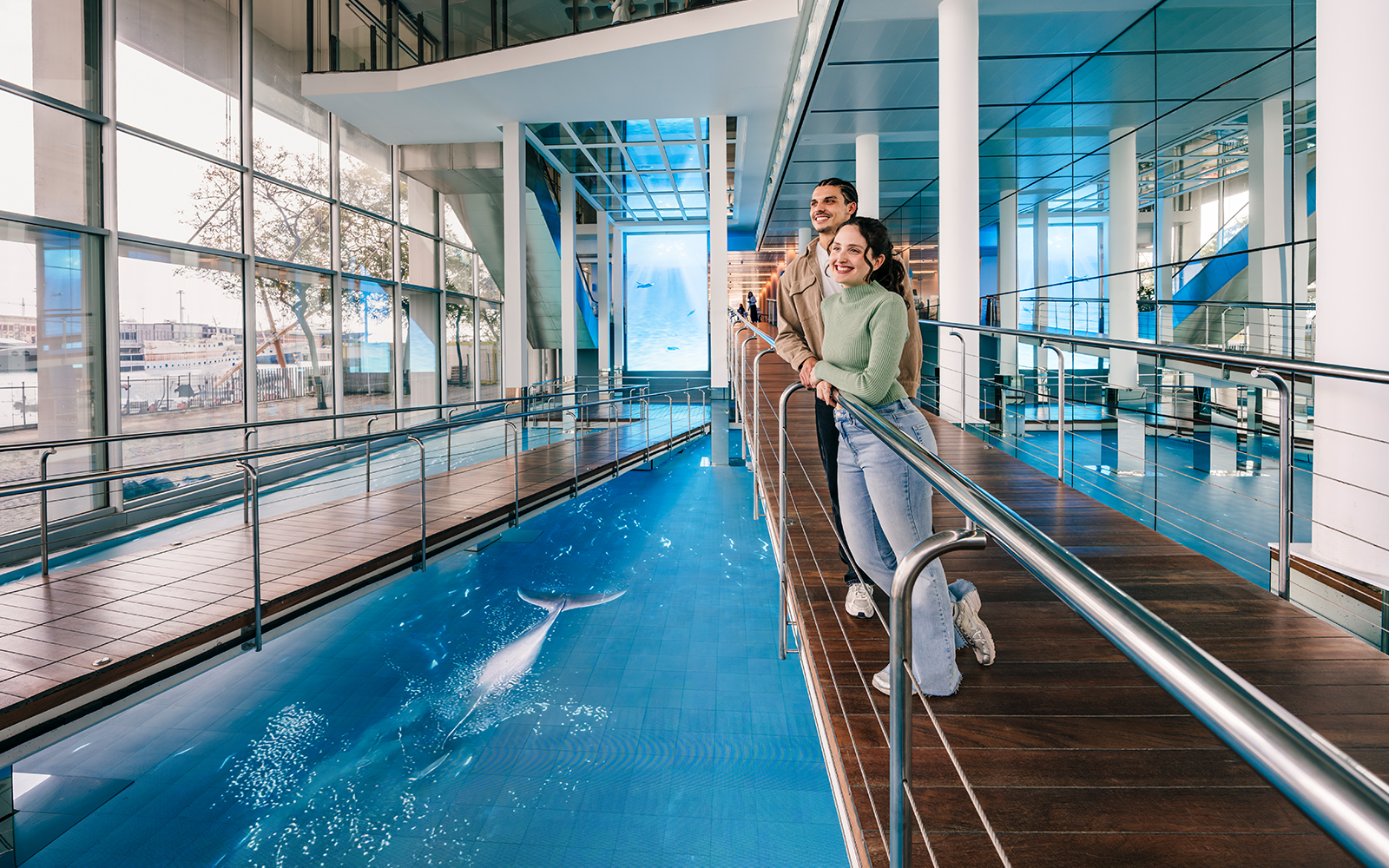 Tourists enjoying the view of the aquarium pool at Barcelona Aquarium.