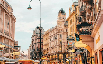 Vienna city street with historic architecture and shop signs, part of a self-guided exploration game.