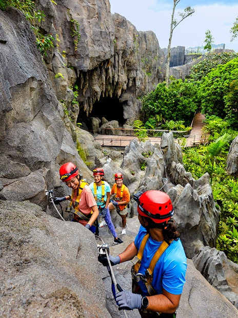 Adventurers climbing rocks in a rainforest cavern in Asia.