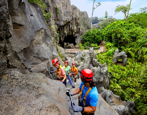 Adventurers climbing rocks in a rainforest cavern in Asia.