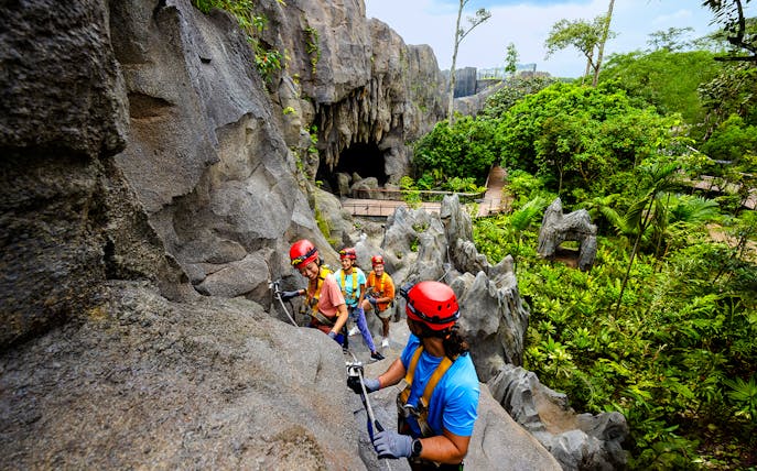 Adventurers climbing rocks in a rainforest cavern in Asia.