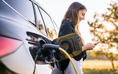 Electric vehicle charging at Keukenhof with person using smartphone nearby.