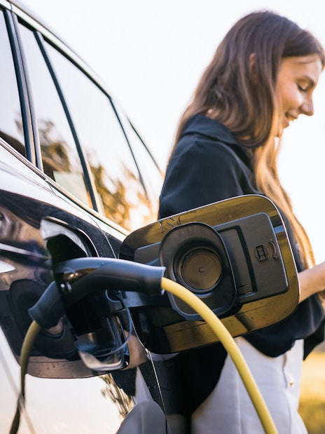 Electric vehicle charging at Keukenhof with person using smartphone nearby.