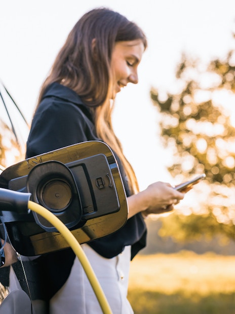 Electric vehicle charging at Keukenhof with person using smartphone nearby.