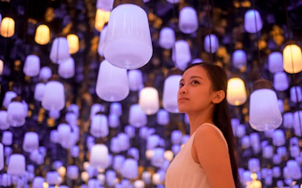 Person admiring illuminated lanterns at teamLab Biovortex, Kyoto Walking Tour.