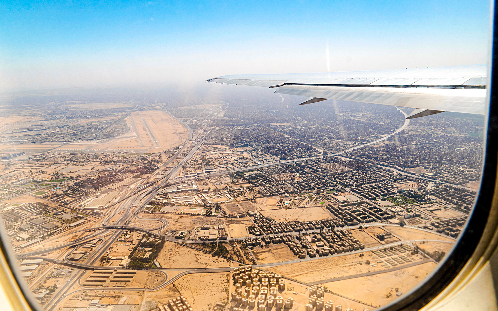 Aerial view of Cairo cityscape from airplane window, showcasing urban layout and desert surroundings.