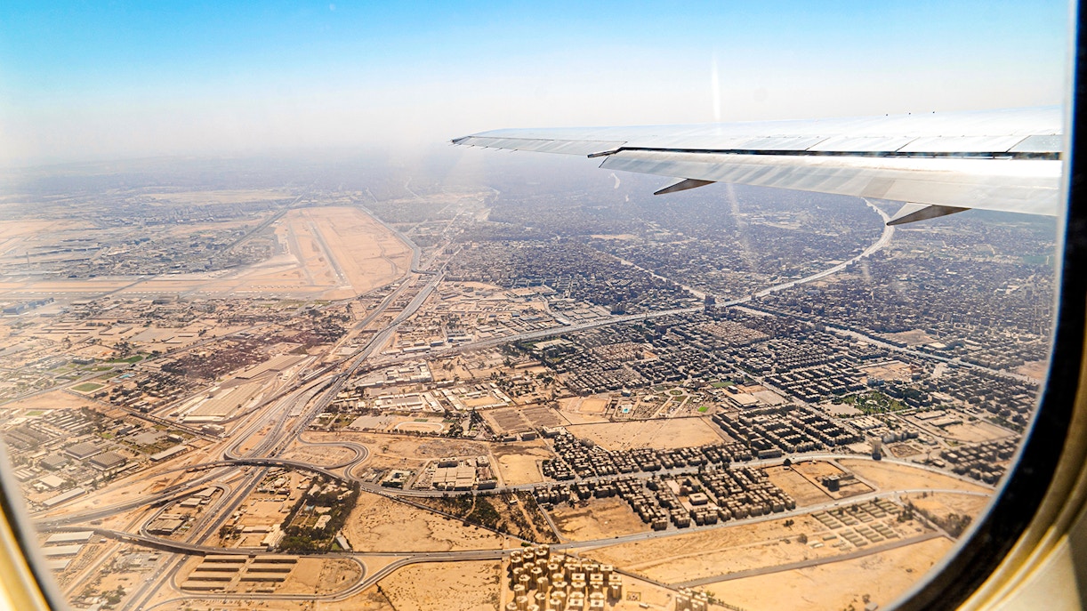 Aerial view of Cairo cityscape from airplane window, showcasing urban layout and desert surroundings.