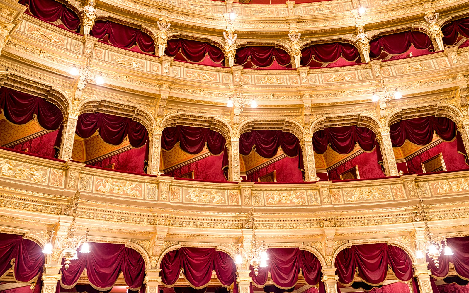 Interior balconies of Hungarian State Opera House, Budapest, with ornate gold detailing and red drapery.