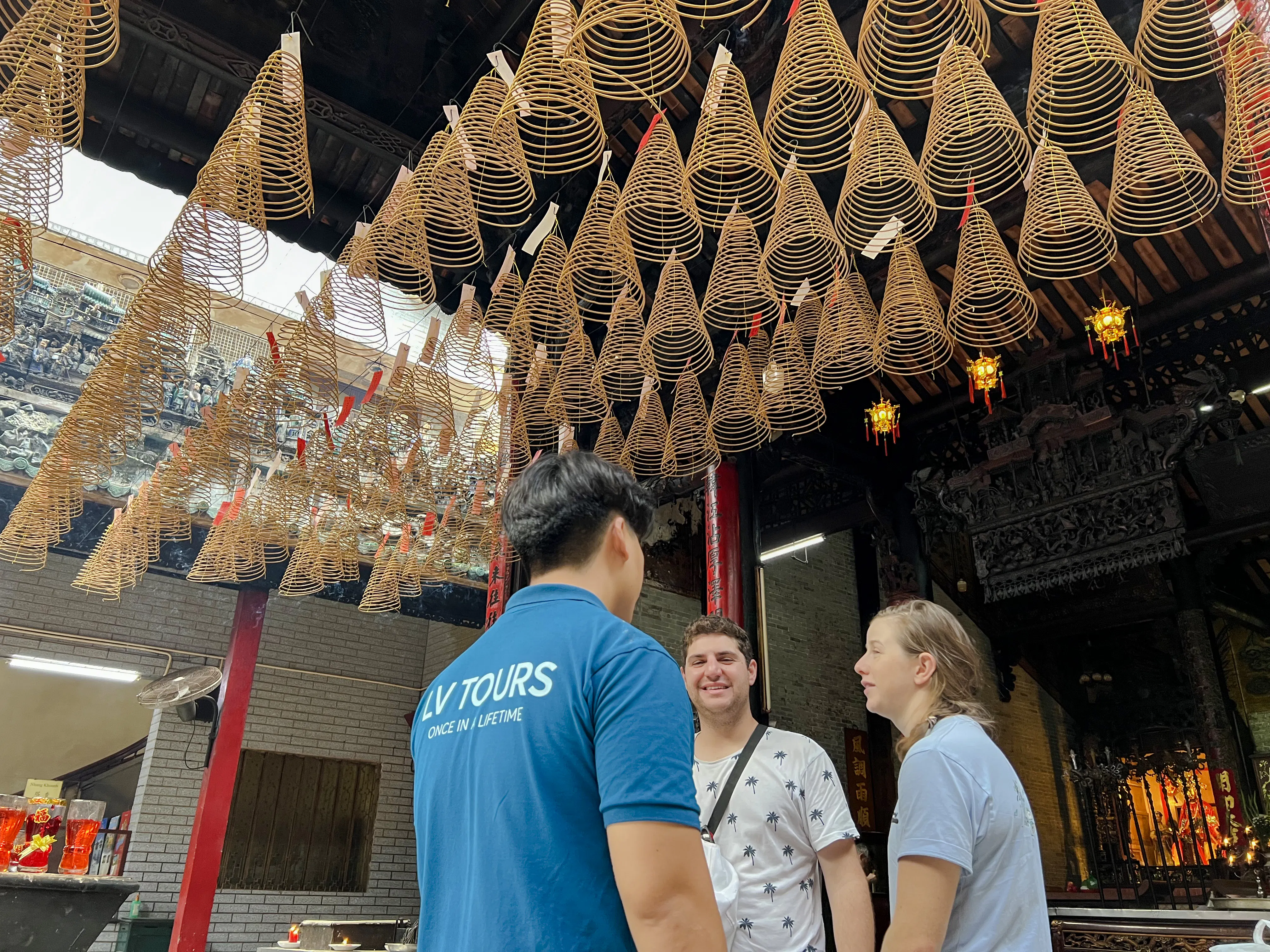Tourists with guide under incense coils at a temple in Ho Chi Minh City on Saigon Hidden Gems Day Tour.