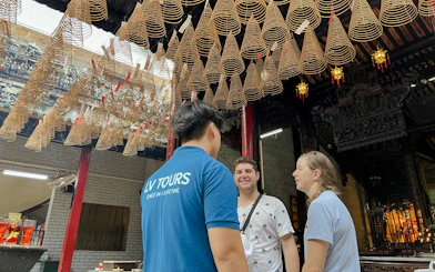 Tourists with guide under incense coils at a temple in Ho Chi Minh City on Saigon Hidden Gems Day Tour.