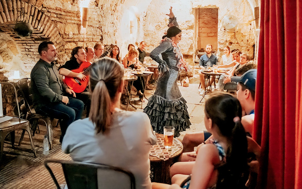 Flamenco dancer performing at Tablao Arab Baths of Santa María with audience and guitarist.