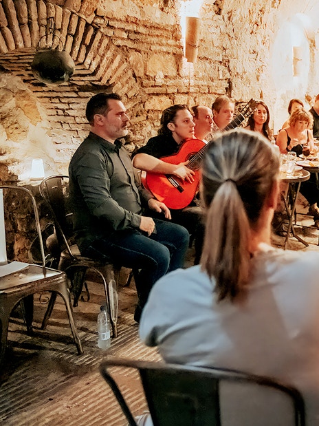 Flamenco dancer performing at Tablao Arab Baths of Santa María with audience and guitarist.