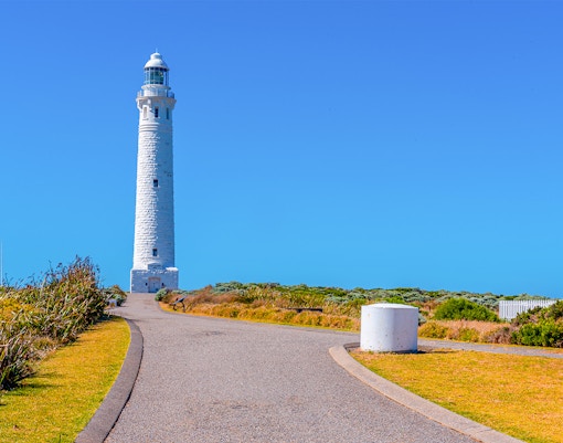 Margaret River Lighthouse with surrounding coastal landscape under clear blue sky.