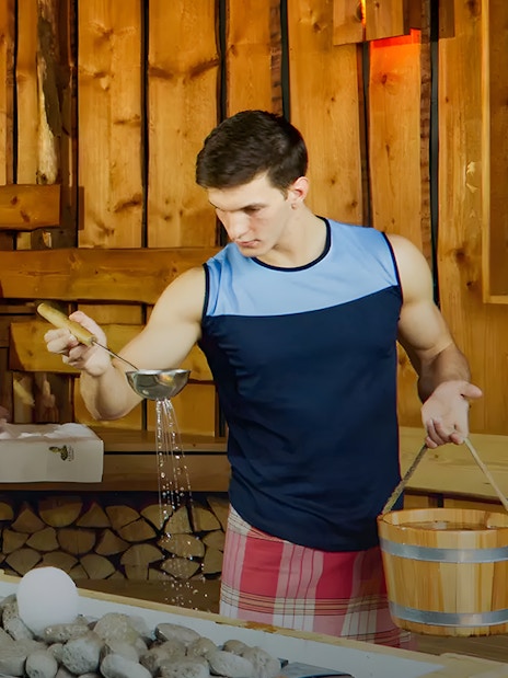 Man pouring water on sauna stones at Bavaria Sauna, Therme Bucuresti.