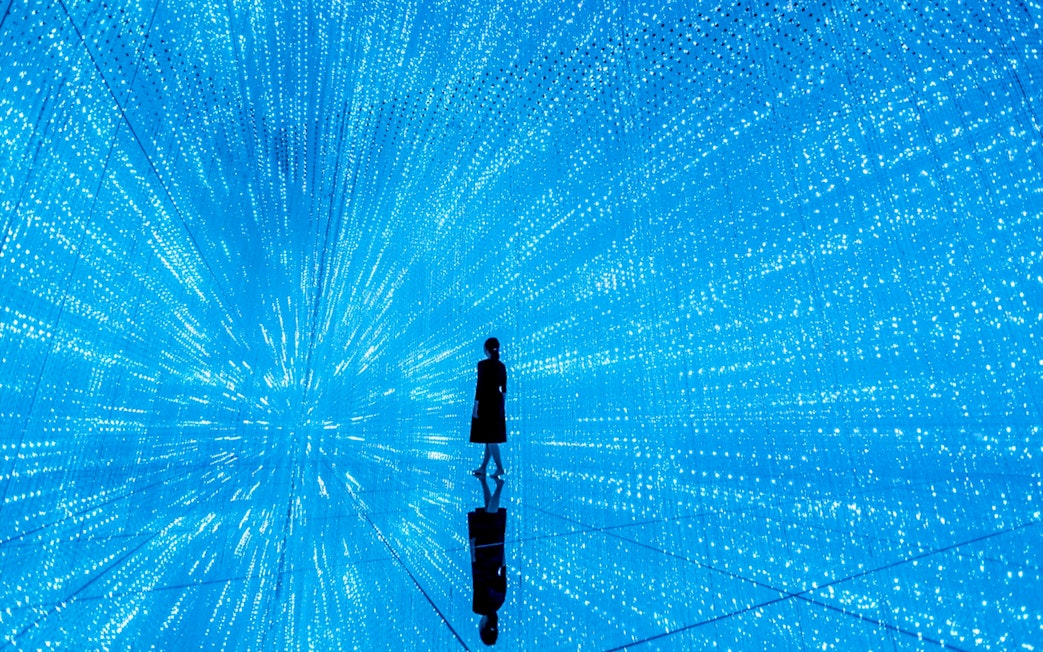 Person standing in immersive digital art installation at teamLab SuperNature Macau.